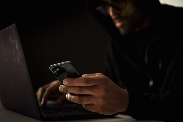 Photo by Sora Shimazaki: https://www.pexels.com/photo/crop-ethnic-hacker-with-smartphone-typing-on-laptop-in-dark-room-5935792/